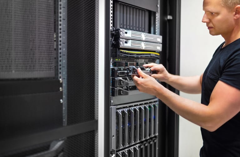 Confident mid adult male IT consultant monitors servers in data center